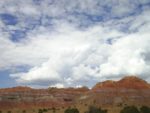 a cloudy sky over a red mountain