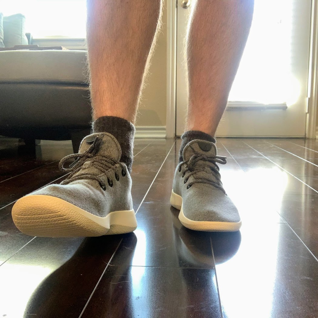 a person's legs and feet in grey shoes