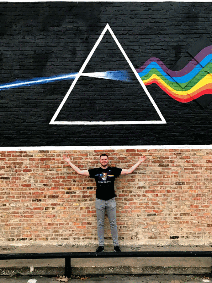 a man standing in front of a brick wall with a triangle painted on it