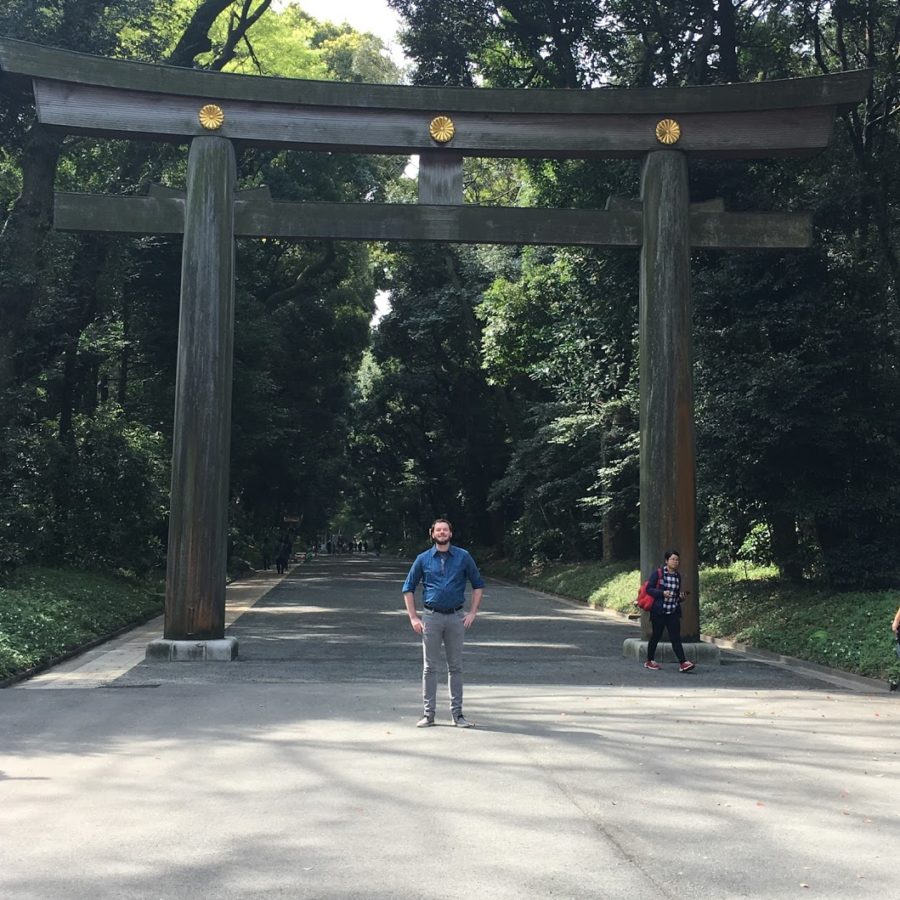 a man standing in front of a large wooden arch
