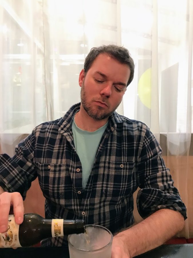 a man sitting at a table with a bottle of wine