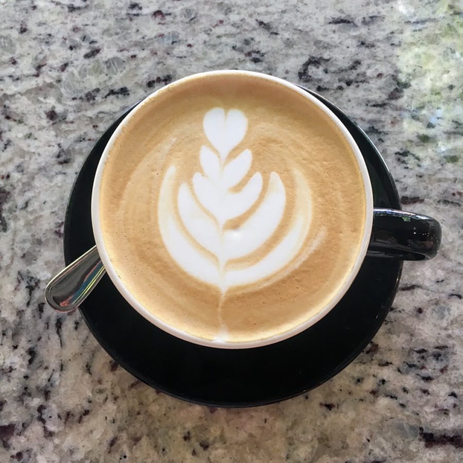 a cup of coffee with a leaf design in the foam