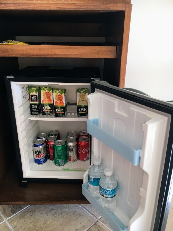 a mini fridge with cans of soda and water