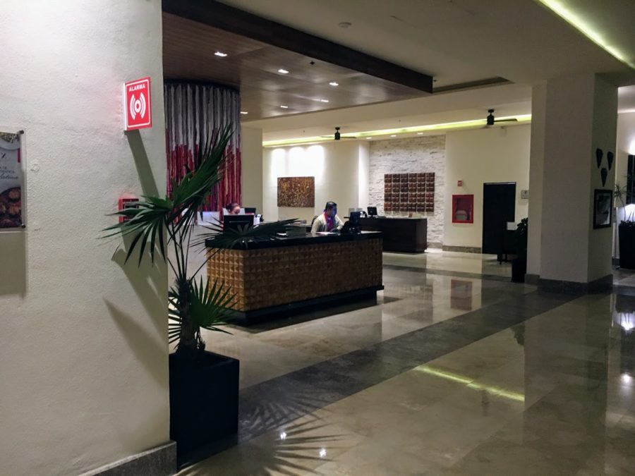 a lobby with a palm tree and a person at the counter