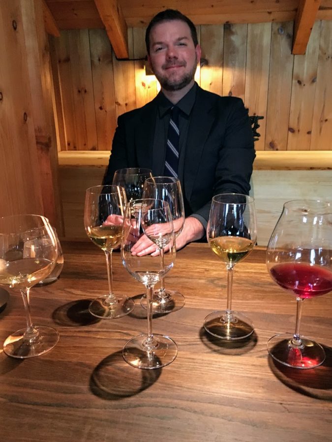 a man sitting at a table with many wine glasses