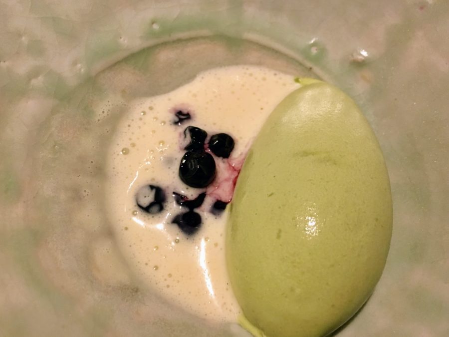 a green ice cream and blueberries in a glass bowl