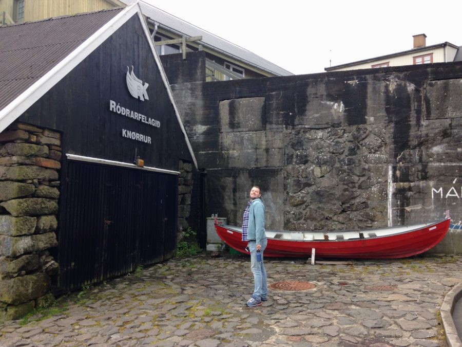 a man standing in front of a building with a boat