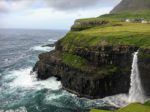 a cliff with a waterfall and a house on it