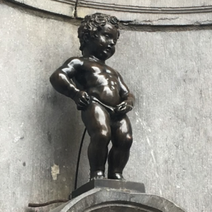 a statue of a naked child with Manneken Pis in the background