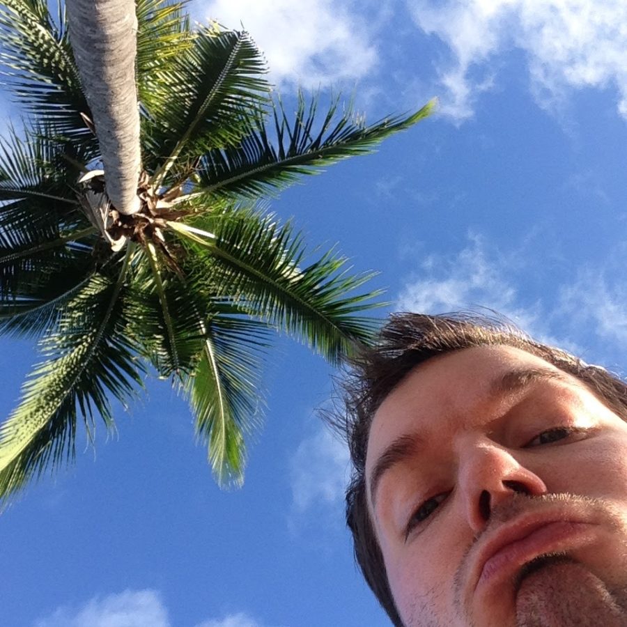a man sticking his tongue out under a palm tree