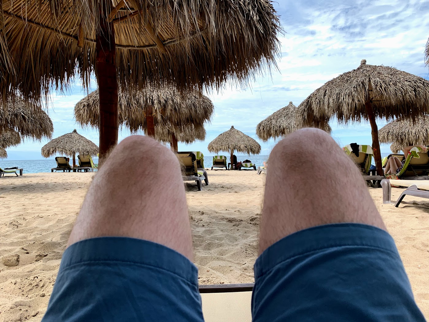 a person's legs in a lounge chair on a beach