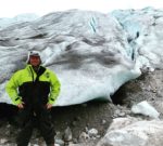 a man standing in front of a large glacier
