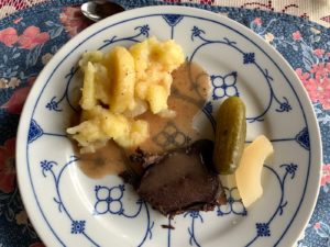 a plate of food with a pickle and a piece of meat