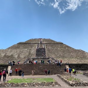 a group of people on a pyramid with Pyramid of the Sun in the background