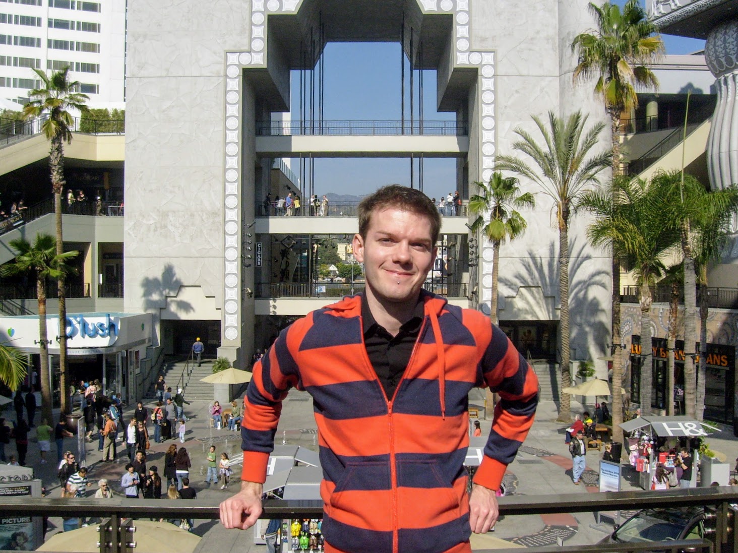 a man standing in front of a building with palm trees and people