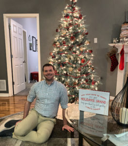 a man sitting on the floor in front of a christmas tree