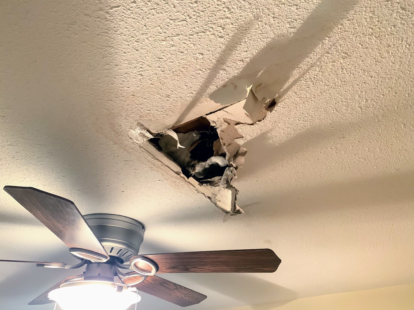 a ceiling fan and a hole in the ceiling