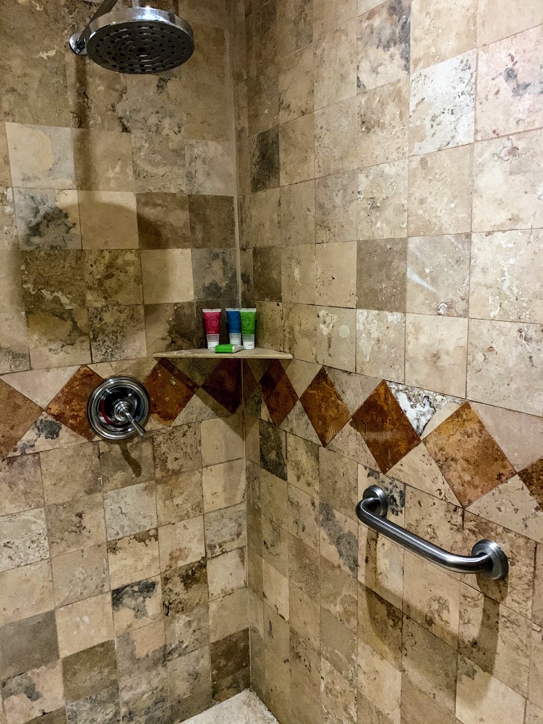 a shower with a shelf and a handle