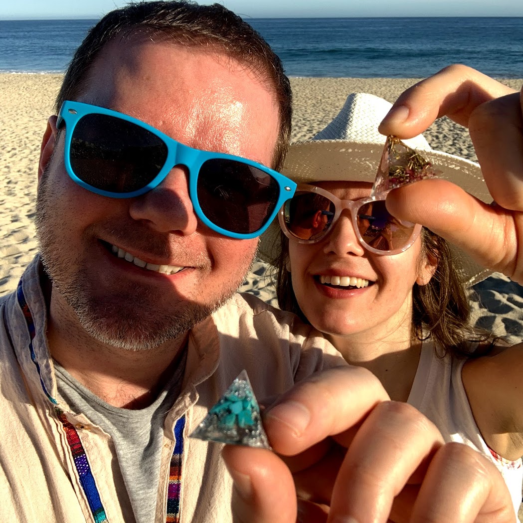 a man and woman holding a small piece of jewelry on a beach