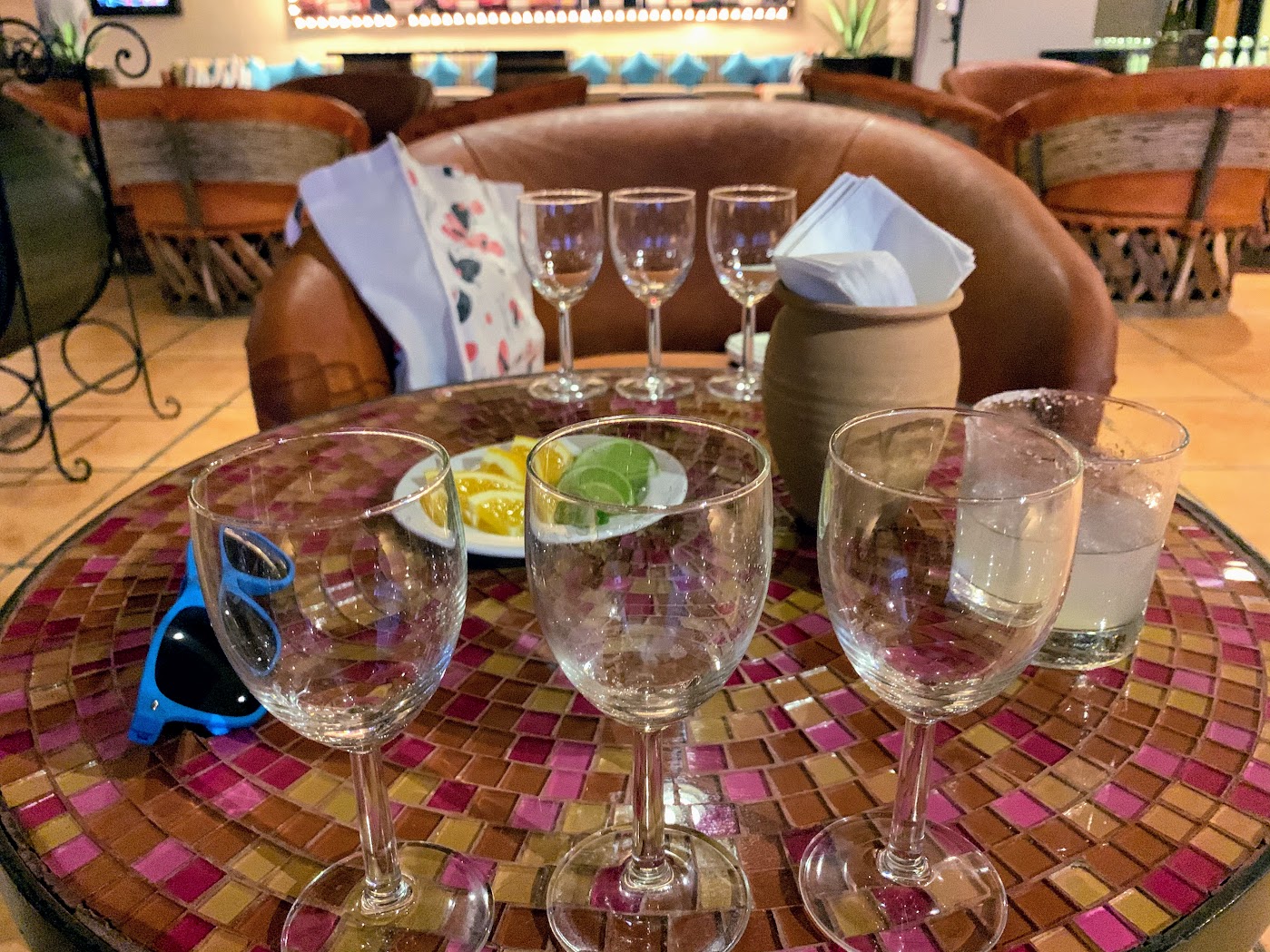 a table with wine glasses and a pitcher of lemons