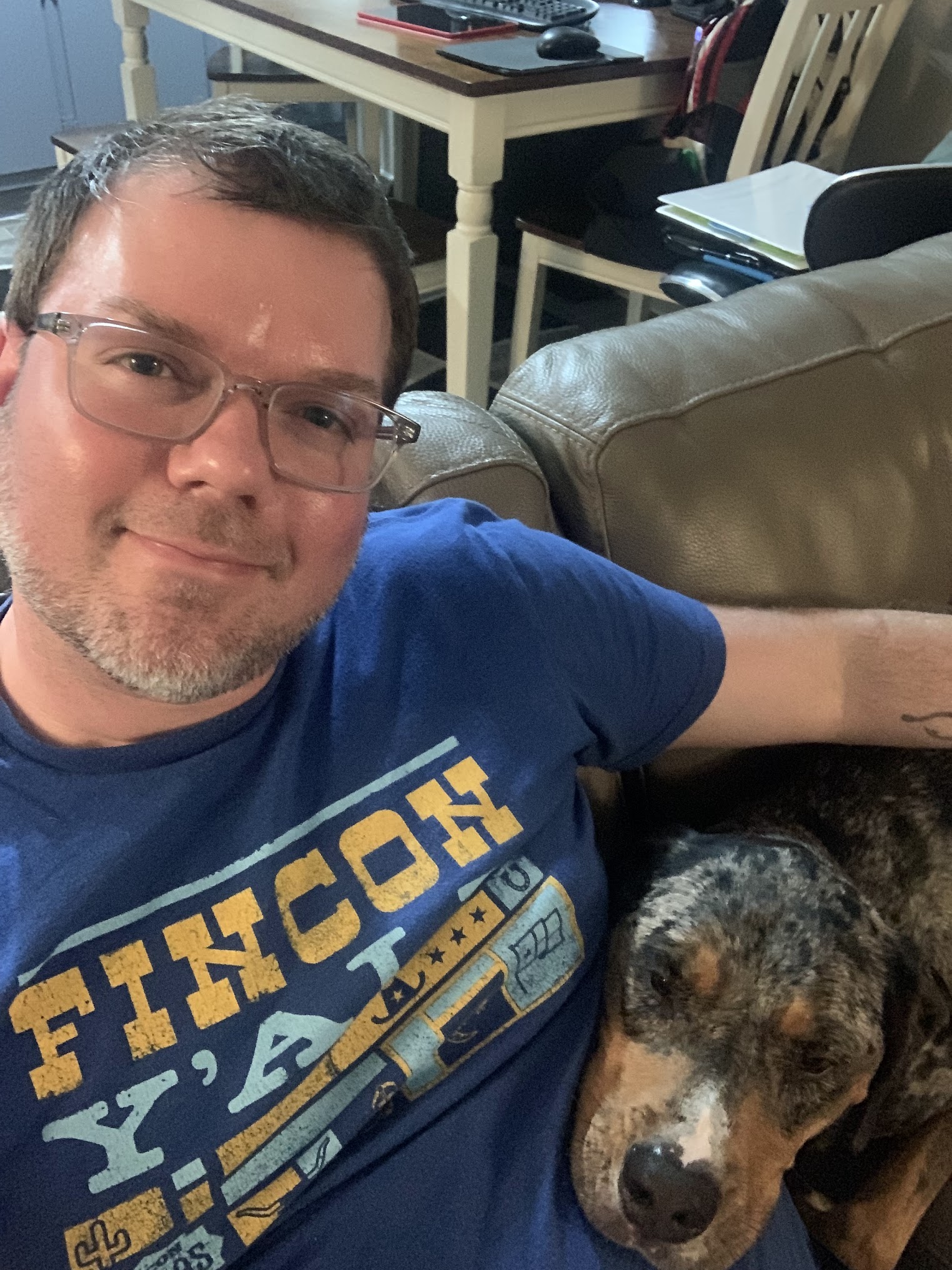 a man with glasses and a dog on a couch