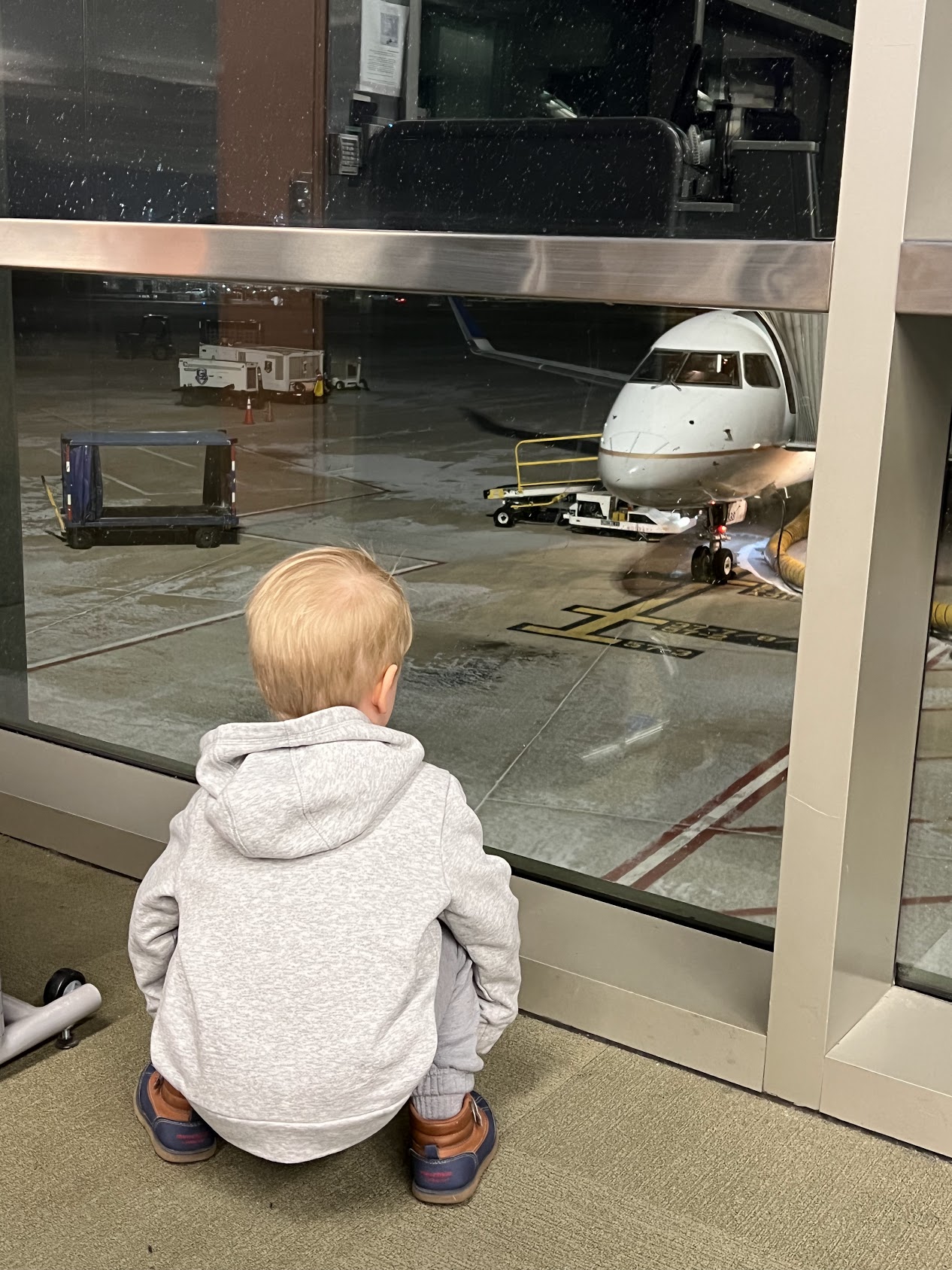 a boy sitting on the floor looking at an airplane