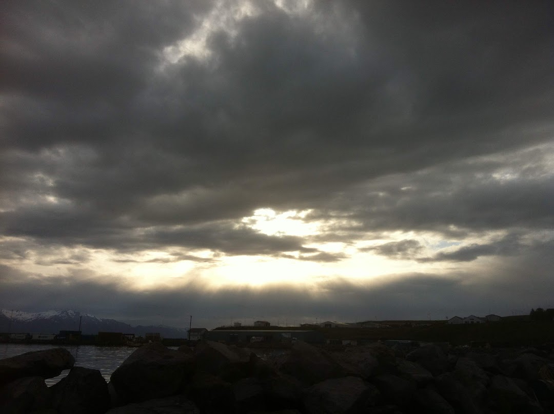 sun shining through clouds over a body of water
