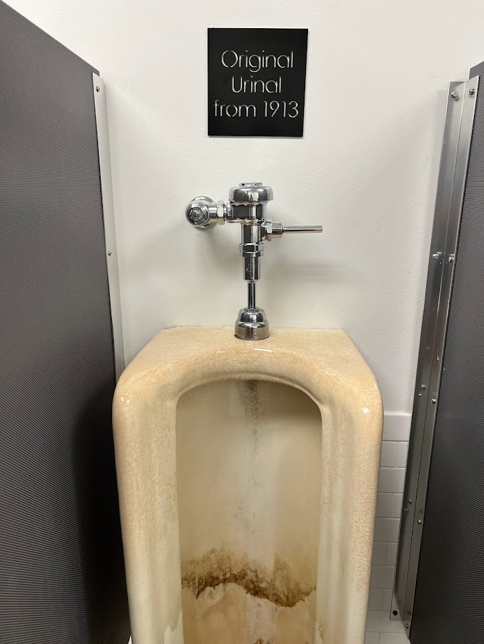 a urinal with a sign on the wall
