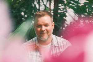 a man smiling in front of plants