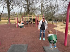 a woman and two kids on swings at a park