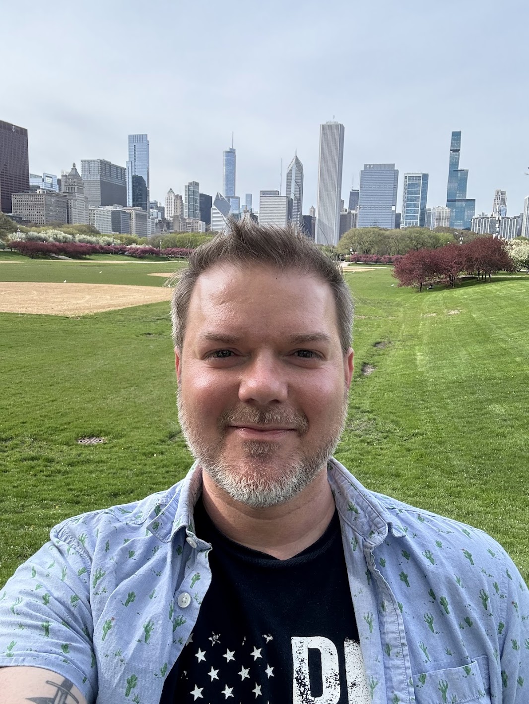 a man taking a selfie in a park with a city in the background