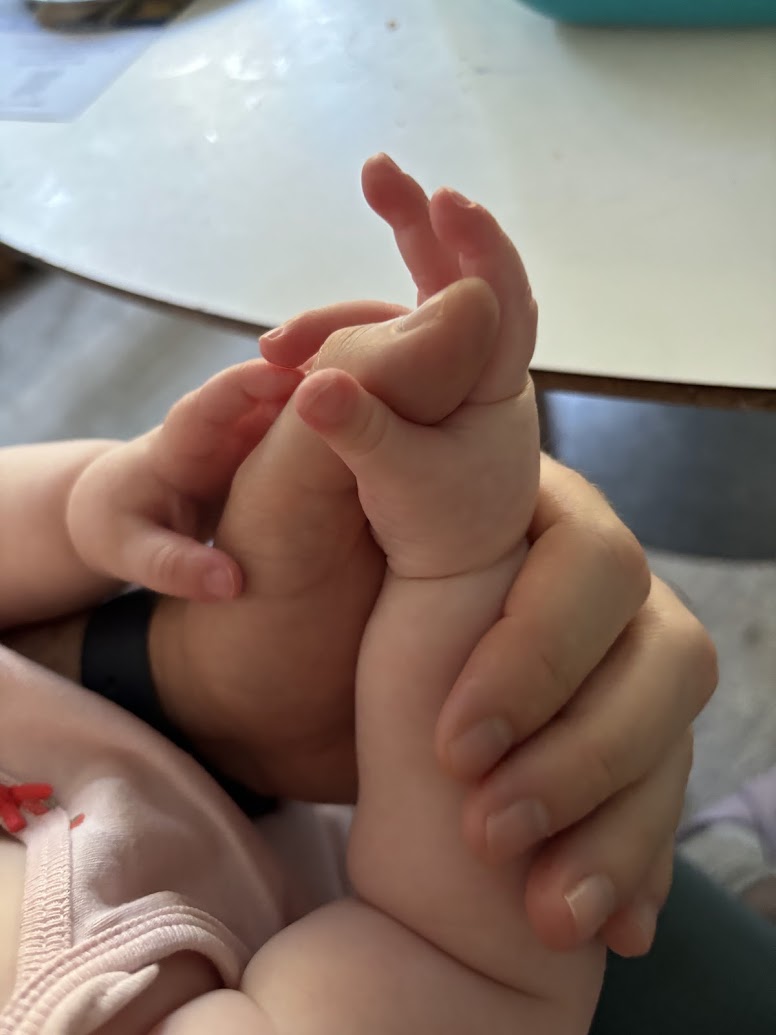 a baby's hand holding a baby's foot