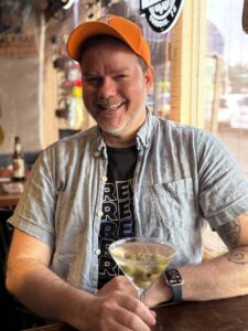 a man wearing a hat and holding a martini glass